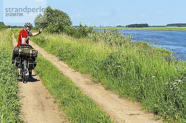 Radfahrer mit Taschen auf einem Fahrrad  ein Mann auf einem Fahrrad reist im Sommer entlang des Flusses  Neman Fluss  Slavsky Bezirk  Kaliningrad Region  Russland  8. Juni 2019  Europa