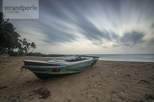 Strand  mit Boot und Blick auf das Meer am Abend bei Sonnenuntergang. Landschaft mit Wolken in Induruwa  Bentota Beach  Sri Lanka  Indien  Asien