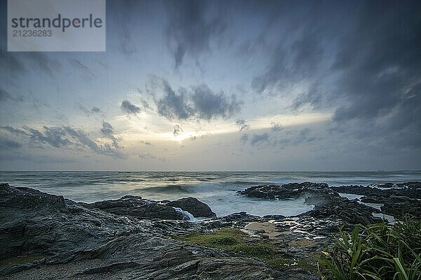 Strand  mit Lavafelsen und Vegetation  Blick auf das Meer am Abend bei Sonnenuntergang. Landschaft mit Wolken in Induruwa  Bentota Beach  Sri Lanka  Indien  Asien