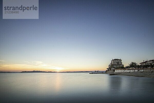 View over the sea into the sunset. Landscape taken with the historical landmark of the Byzantine tower of Prosphorion on the coast of Ouranoupoli  Thessaloniki  Central Macedonia  Greece  Europe