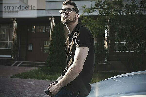 Portrait of an handsome smiling caucasian business man near his car with phone