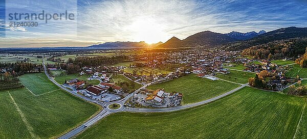 Luftaufnahme eines Dorfes in einer weitläufigen Landschaft bei Sonnenuntergang  umgeben von Bergen  Bad Feilnbach