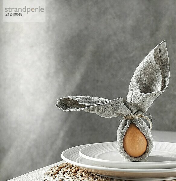 Food  Festive Easter table setting. Funny Easter bunny made of egg and linen napkin on plate. Gray background