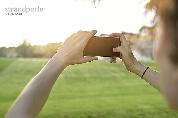 Close-up guy takes pictures of nature  beautiful views on his smartphone. summer mood