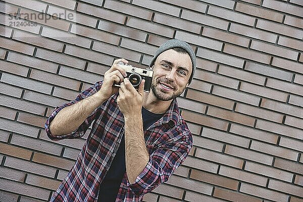 Mann mit Retro Fotokamera Mode Reisen Lifestyle im Freien  während stehend gegen Backsteinmauer Hintergrund