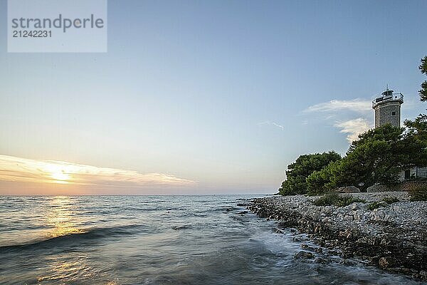 Beautiful sunset in a landscape on a rocky coast with a prominent lighthouse and pine forest. View over the coast to the building  on the Mediterranean Sea  Vir  Dalmatia  Croatia  Adriatic Sea  Europe