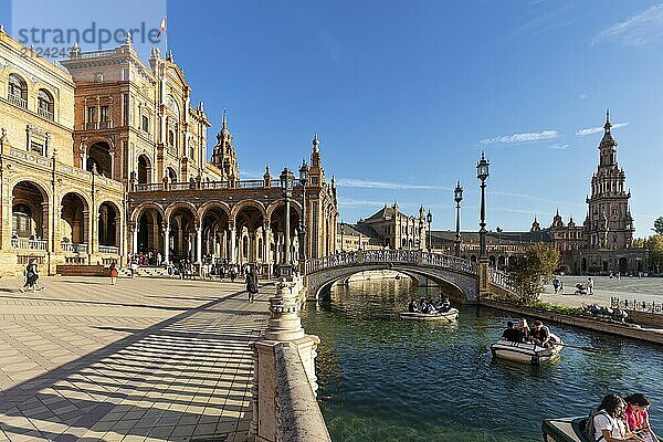 Leute genießen Bootsfahrten auf dem Wasser neben einer geschwungenen Brücke unter der Sonne  Sevilla