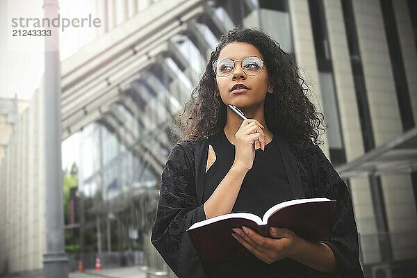 Self employed Mixed-race female entrepreneur busy writing in her notebook