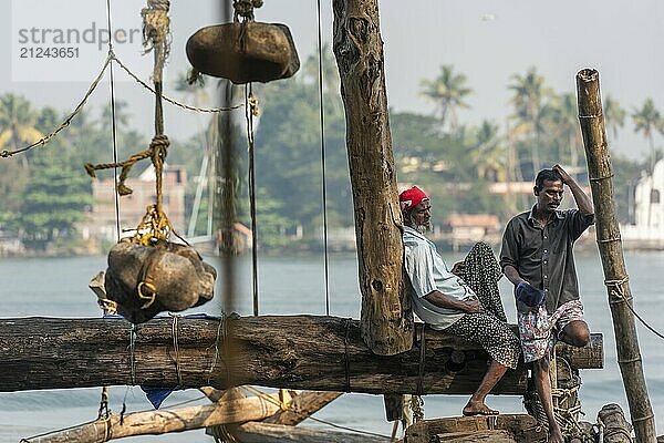 Fishermen resting  heavy stones attached to ropes  Chinese fishing nets  sunset  Arabian Sea coast  Fort Cochin  Kochi  Kerala  South India  India  Asia