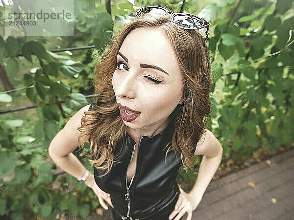 Close-up of a positive flirtatious European woman. The girl smiles happily  blinks playfully at the camera  flirts with you. Facial expressions and human emotions. nature