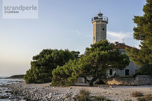 Beautiful sunset in a landscape on a rocky coast with a prominent lighthouse and pine forest. View over the coast to the building  on the Mediterranean Sea  Vir  Dalmatia  Croatia  Adriatic Sea  Europe