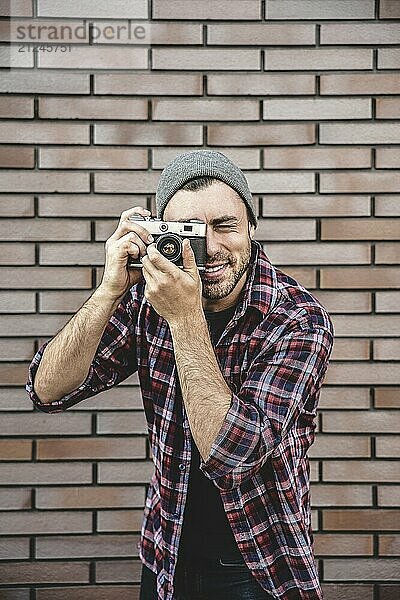 Mann mit Retro Fotokamera Mode Reisen Lifestyle im Freien  während stehend gegen Backsteinmauer Hintergrund