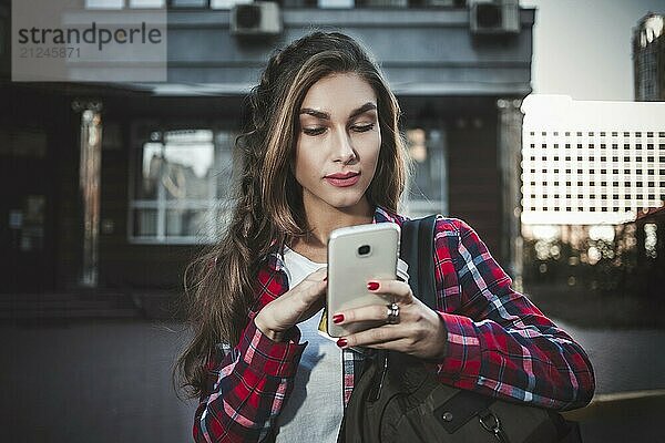 Young girl talking on the phone in the street surfing on the phone