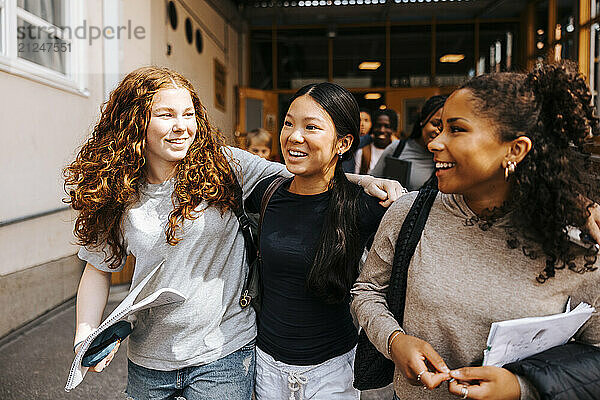 Happy multiracial female students walking on school campus