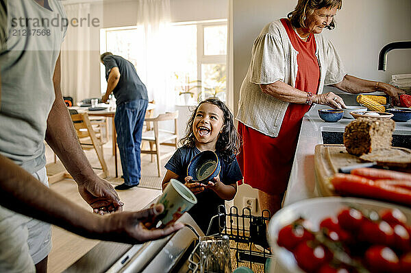 Happy son holding bowl while standing in kitchen with family at home