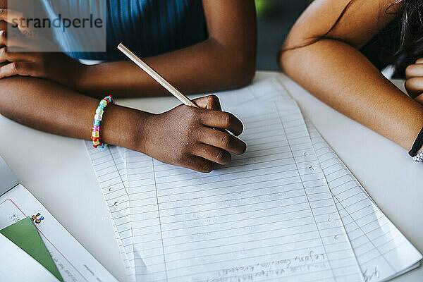 Cropped image of girl holding pencil on paper