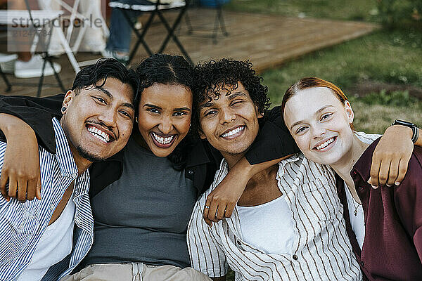 Portrait of happy male and female friends posing in back yard at dinner party