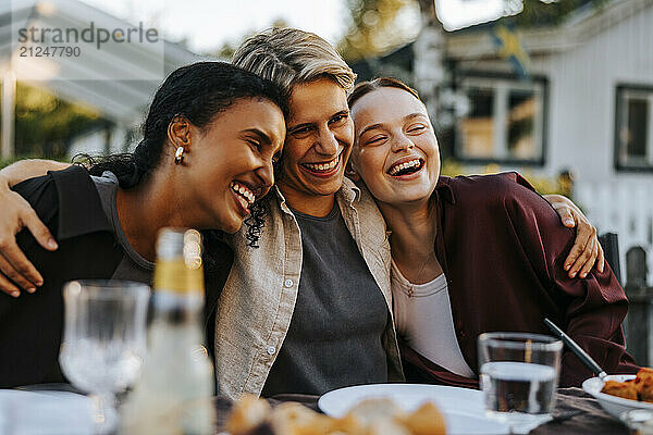 Happy young woman embracing female friends in back yard at social gathering