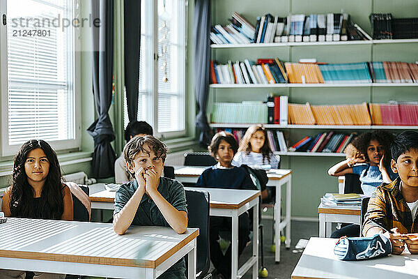 Group of students sitting near desk in classroom at school