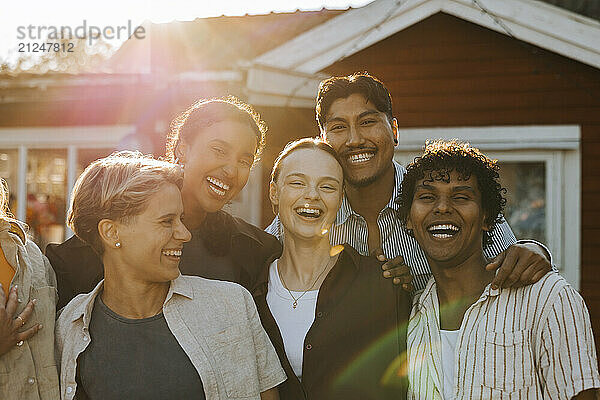 Portrait of cheerful male and female friends in back yard at sunny day during social gathering