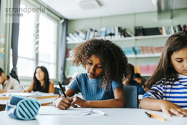 Focused schoolgirls giving exam while sitting in classroom at elementary school