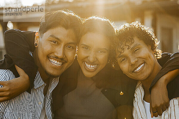 Portrait of happy male and female friends posing in back yard at sunny day at social party