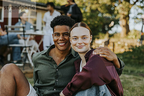 Portrait of smiling young man with arm around female friend in back yard