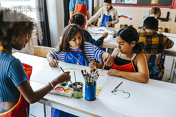 High angle view of female students painting on paper during art class in elementary school