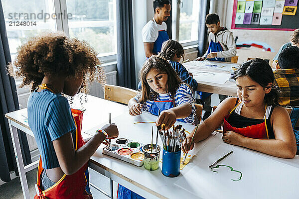 Female students painting during art class in elementary school