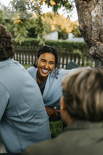 Happy young woman talking with female friend in back yard at dinner party