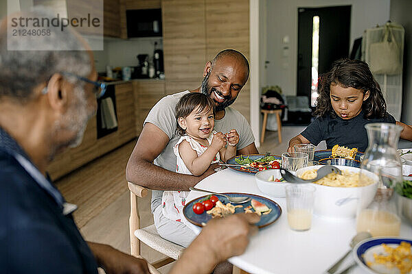 Happy multigenerational family having breakfast on dining table at home