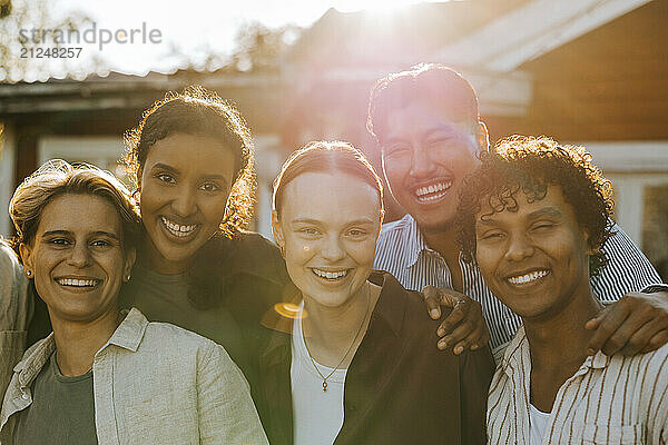 Portrait of happy male and female friends in back yard at sunny day during social gathering