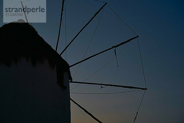 Silhouette of a traditional windmill against a twilight sky.