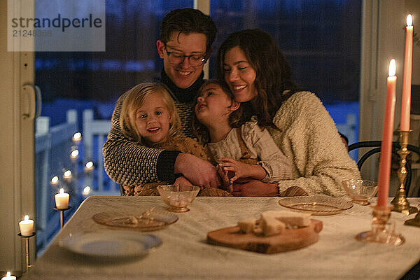 A family enjoys a cozy candlelit dinner  smiling and embracing with love and warmth.