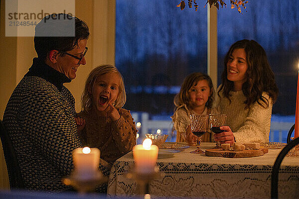 Family enjoying a cozy candlelit dinner with smiles and laughter.