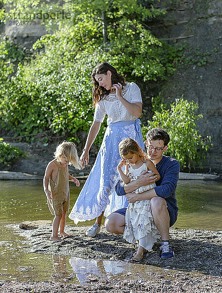 Family enjoying a day out by a water body with two young children and parents  expressing affection and togetherness.