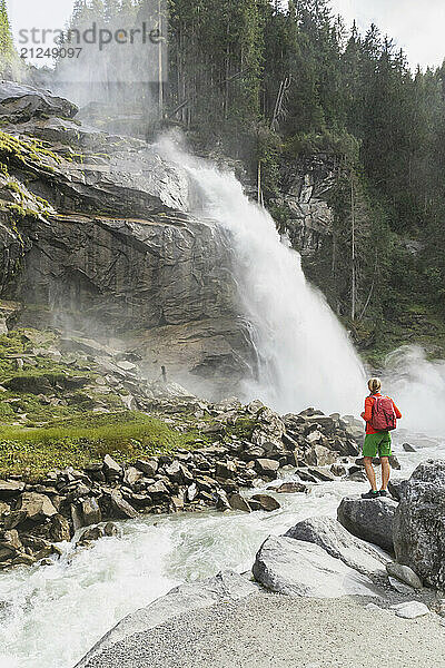 Woman standing on rocks looking at Krimml Waterfalls in Hohe Tauern National Park  Austria.