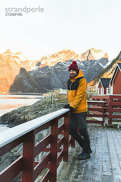 Man enjoying view of Lofoten Islands in Norway from a wooden deck during dawn.