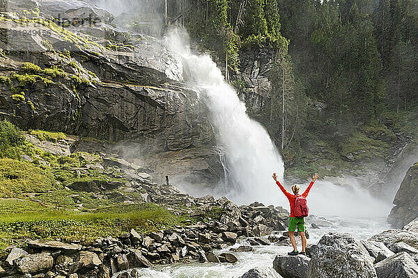 Hiker cheering at Krimml Waterfalls in Hohe Tauern National Park  Austria.