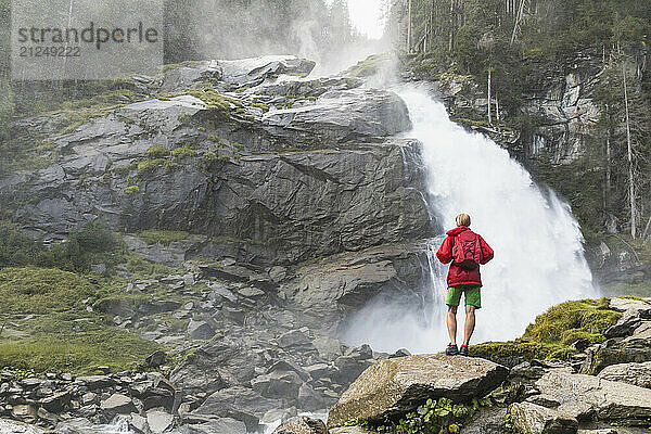 Woman standing on rocks and looking at Krimml Waterfalls in Hohe Tauern National Park  Austria.