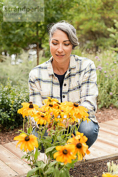 Woman kneeling in front of yellow daisies