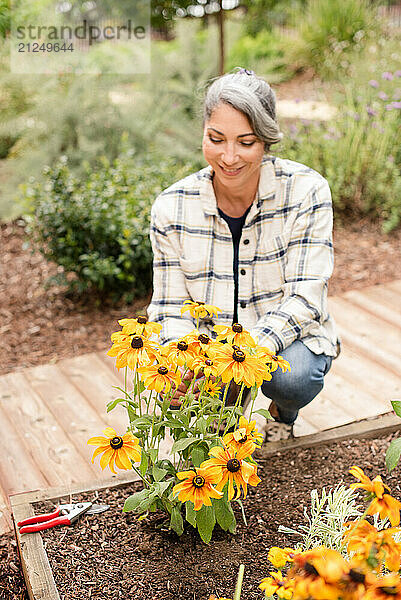 Woman smiling at yellow daisies in garden