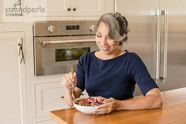 Woman smiling down at yogurt in kitchen