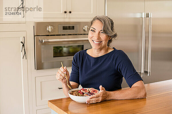 Woman smiling in kitchen holding a bowl of yogurt