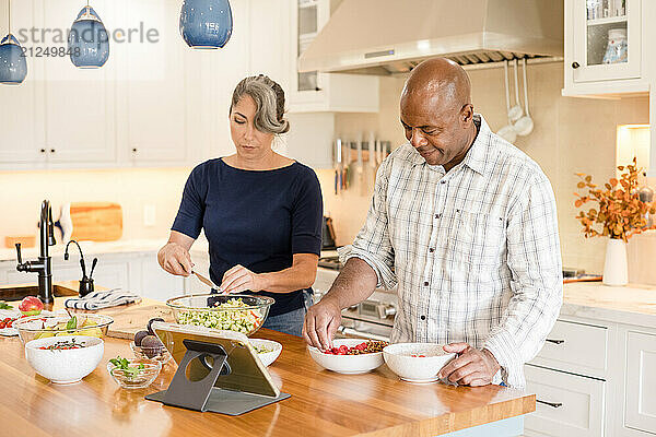 Couple preparing food in the kitchen using a tablet