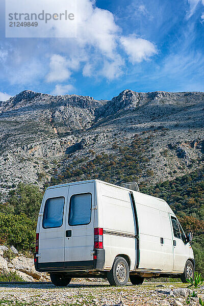 Brown dog looking out of a camper van window on a mountain landscape