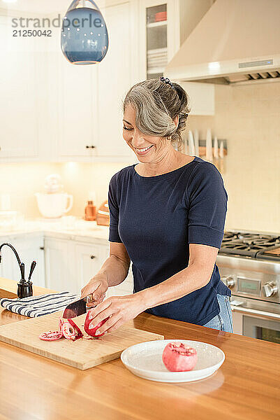 Woman in a kitchen cutting a pomegranate