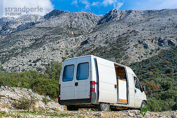 Brown dog looking out of a camper van window on a mountain landscape