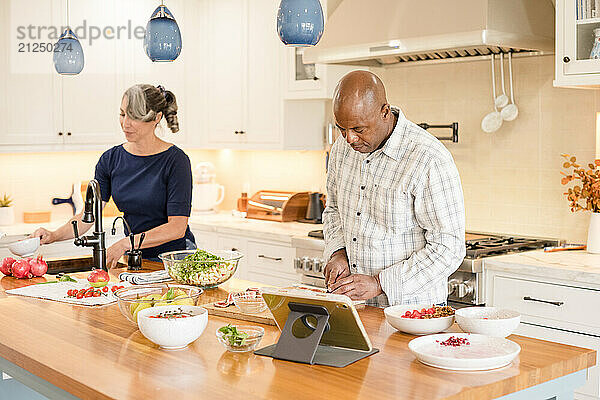 Man and woman in kithcen cooking together with tablet