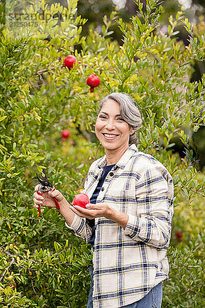 Woman smiling at the camera while holding a pomegranate